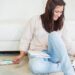 Crawlspace Infestation? Don't Panic. Here's What to Do - smiling woman sitting on the floor with laptop and paperwork